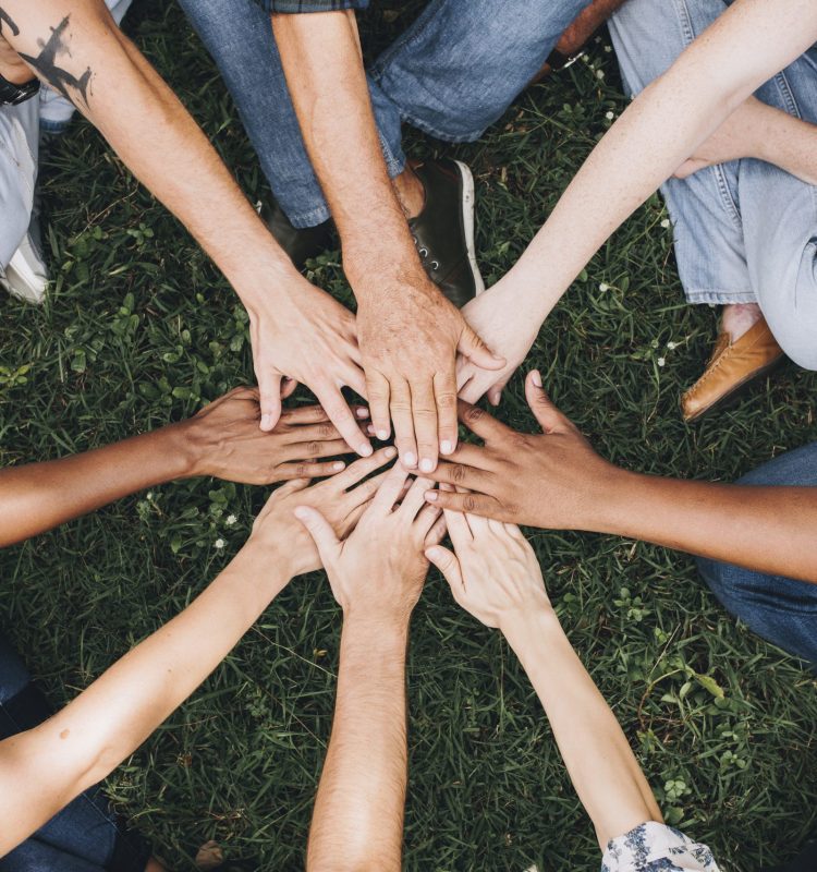 People stacking hands together in the park
